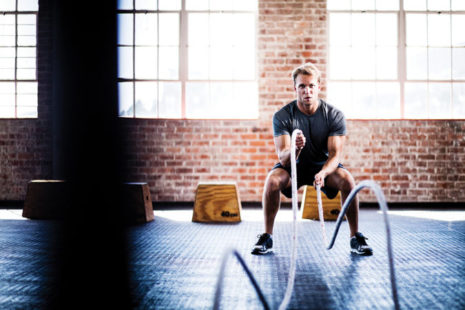 Man doing battle ropes exercise during gym training at gym