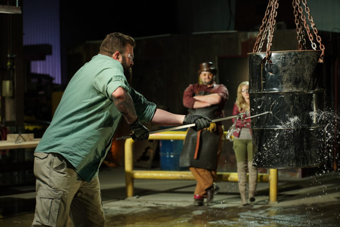 Zeke puncturing hanging barrel with contestants weapon, Trent and Ashley in background.