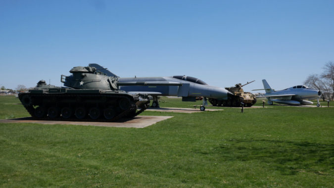 Assortment of various military vehicles and aircraft opposite of old museum building.